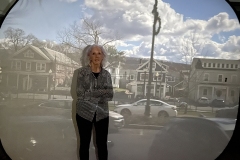 woman standing in front of screen with project of village street using camera obscura