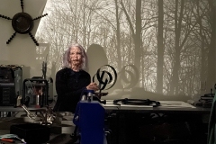 Lonna in Karen Maddens studio with bare tree limbs and branches projected on wall with camera obscura