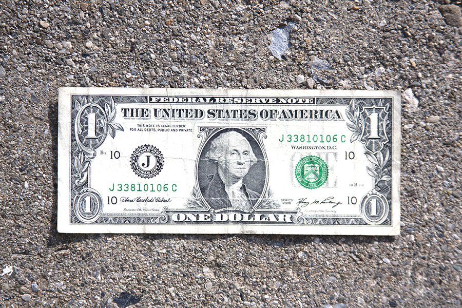 one dollar bill laying flat on concrete