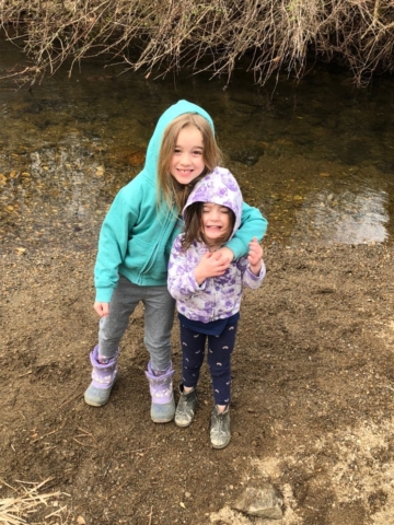 Two young sisters standing near stream