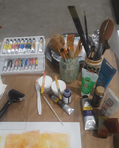 artists table top with paints, brushes, tool and paper