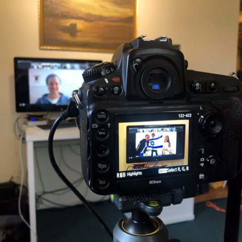 Pro camera with celebration in display window, computer with photos in background