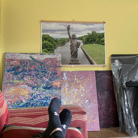 view of paintings and a photo of Statue of Liberty from person laying on couch