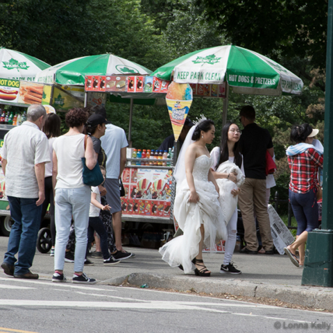 A bride in full gown and headress walking casually with friend in Central Park