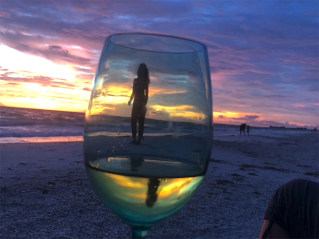beach sundown girl photographed through a wine glass