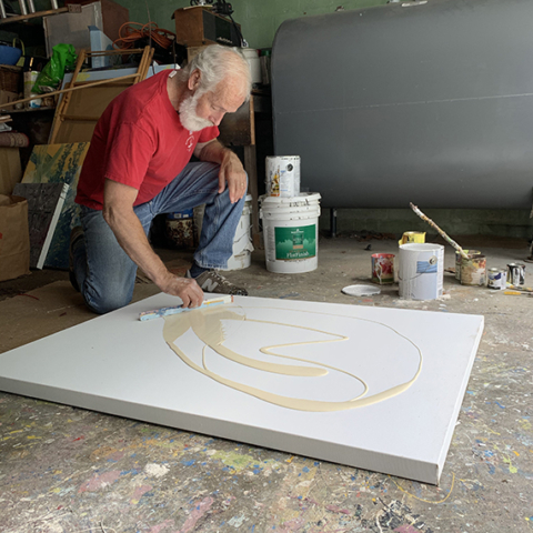 canvas laying on floor artist john colantuono spreading paint