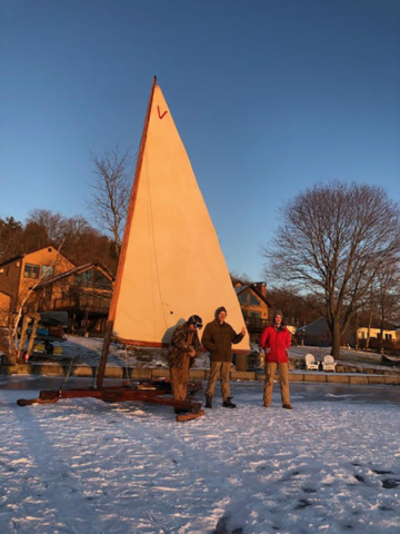 3 people in evening sunlight making repairs to iceboat