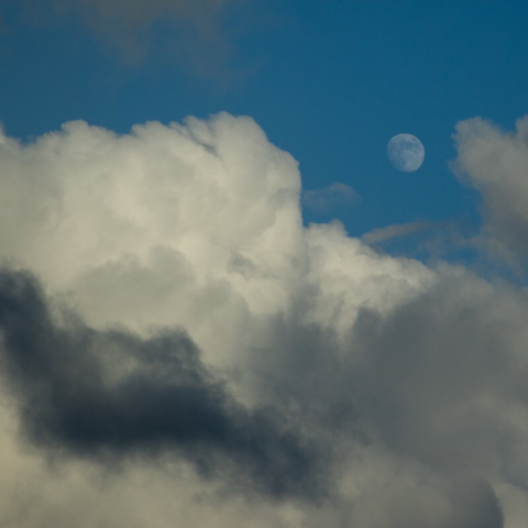 Blue sky white moon large billowing clouds
