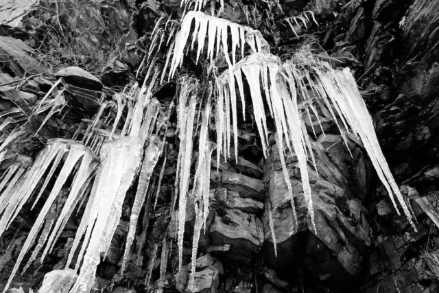 black and white image of icicles on rock face