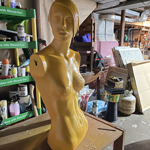 Armless torso of mannequin painted gold in workroom,