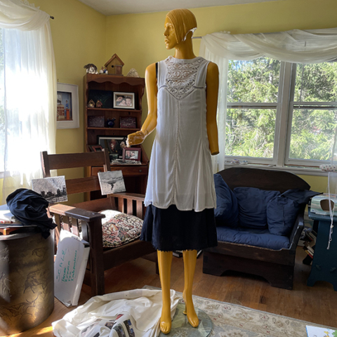 mannequin standing in living room dressed in plain dresses but missing a hand