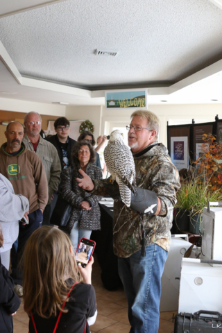 Jim Eyring holing black and white bird of prey while talking to crowd