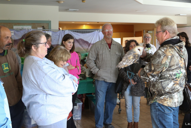 people listening to falconer who is holding owl