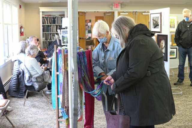 women looking at scarves for sale at show