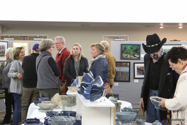 A group of people viewing artwork and pottery