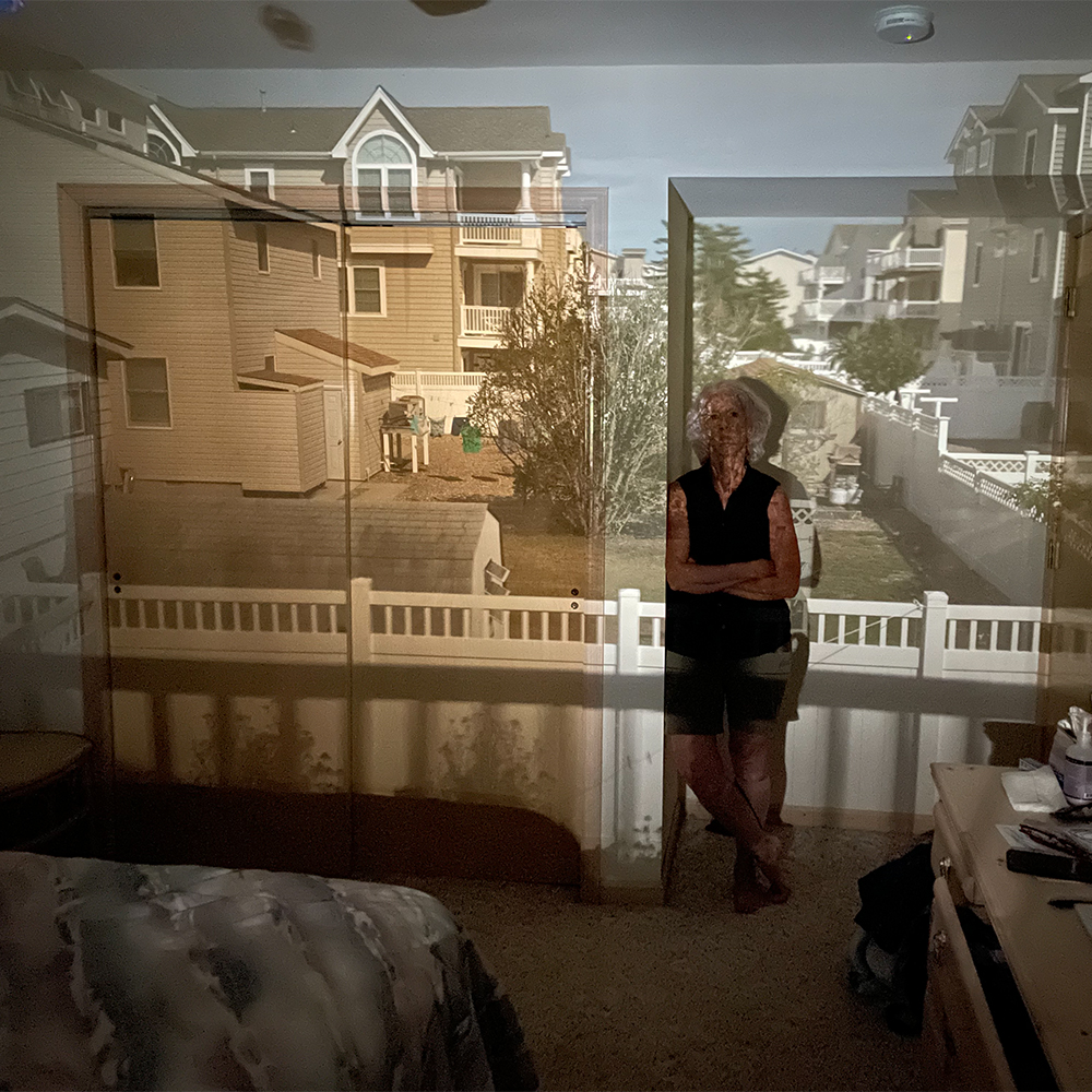 images of houses projected to interior wall with Camera Obscura woman leaning against wall