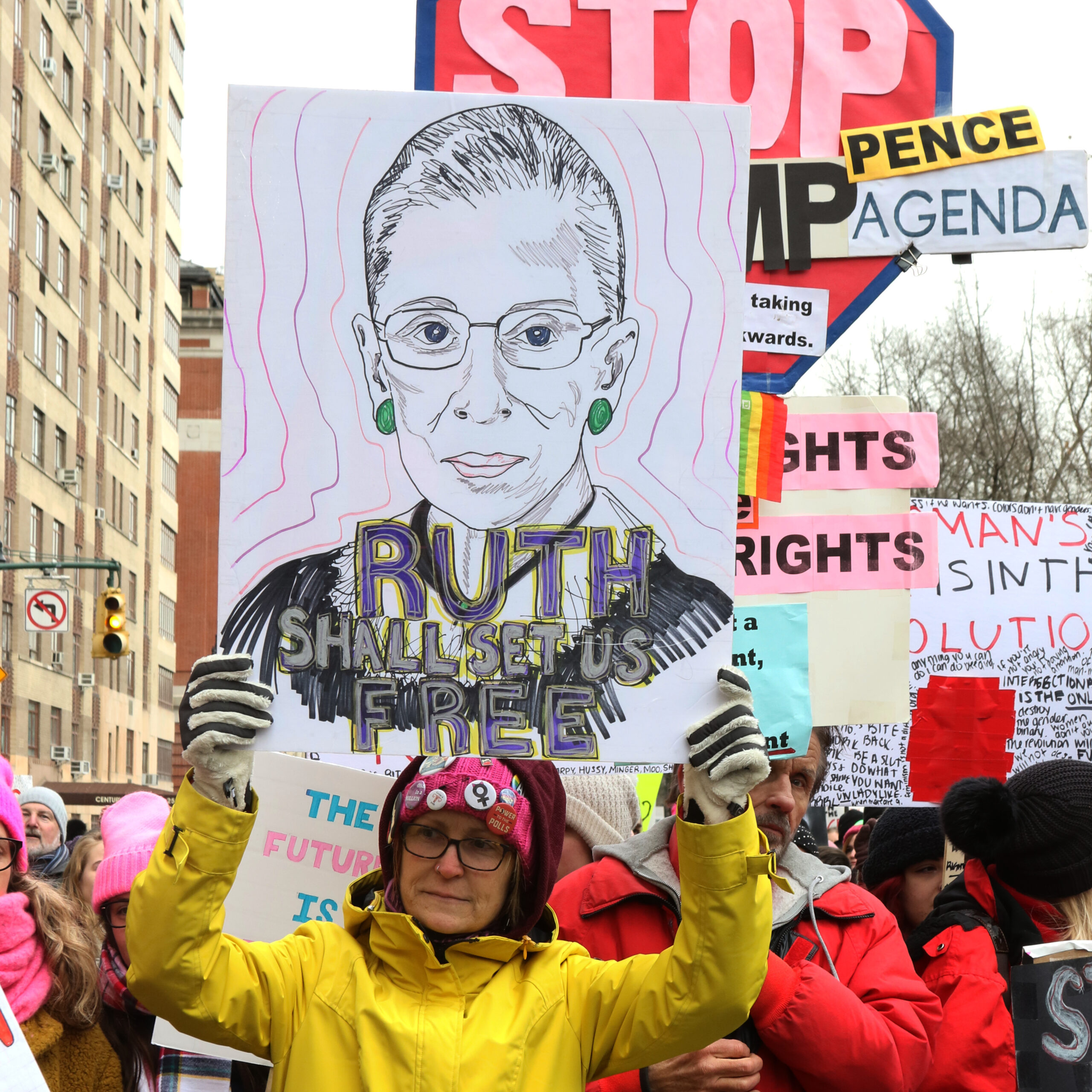Womens March on NYC woman in yellow jacket holding up with sketch of Ruth Bader Ginsberg