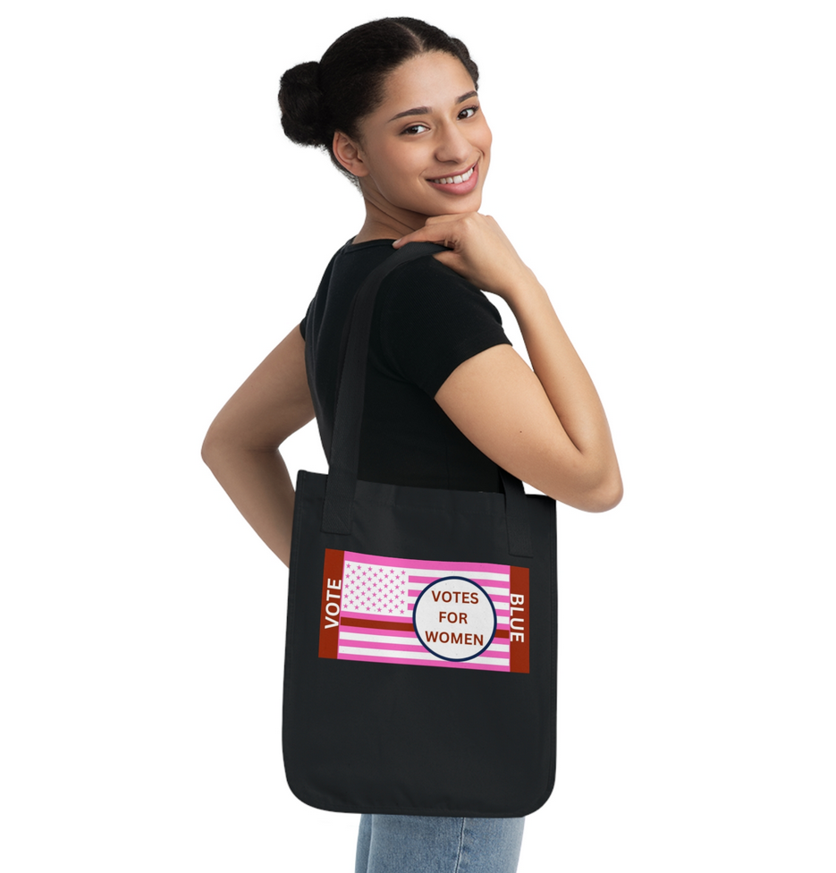 Smiling woman looking over shoulder and carrying a black tote bag with pink womens Lives Matter flag and words votes for women